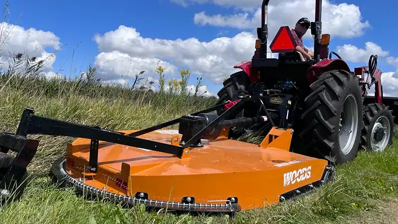 man on tractor mowing with woods rotary cutter